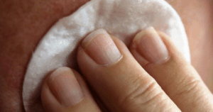 fingers holding cotton pad to skin